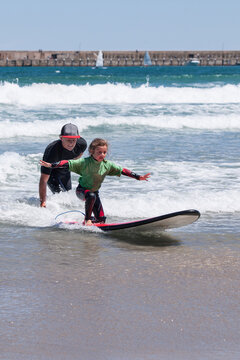 Young Girl Learning to Surf with the help of a surf coach