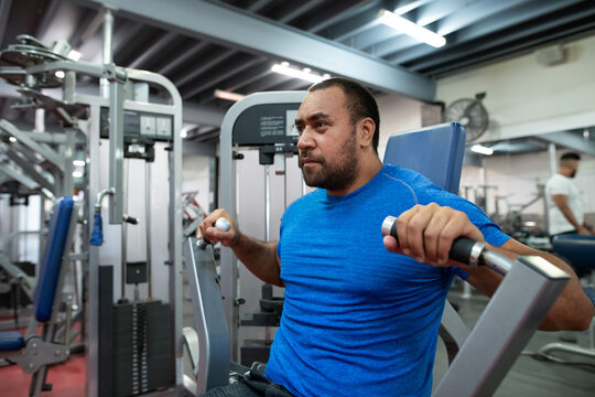 Heavy set man lifting weights at a gym