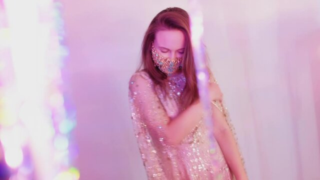 Ethnic festive look. Christmas party. Pandemic fashion. Happy woman in glossy dress golden chain crystal beads face mask going through sparkle cascade curtain posing on camera copy space.