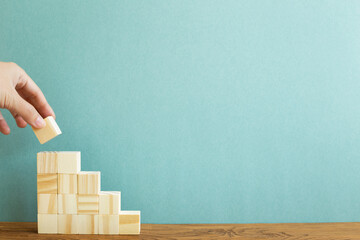 Hand stacking wood block stairs with green background. Business development, growth, success concept