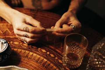 Anonymous Man With Finger Tattoos Rolling A Joint