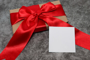 Packed gift with a red ribbon with a white card for writing the text. concept holiday, gift giving, discounts, promotions, Black Friday.