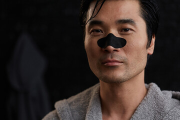 Man in bathrobe using nose strip