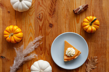 Traditional thanksgiving food on wooden table. Orange delicious homemade pumpkin pie with crust and decorative items. Thanksgiving table setting concept.Top view, close up, copy space, background.