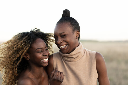 Portrait of two Afro European teenager girls in a natural landscape, with sunset light.