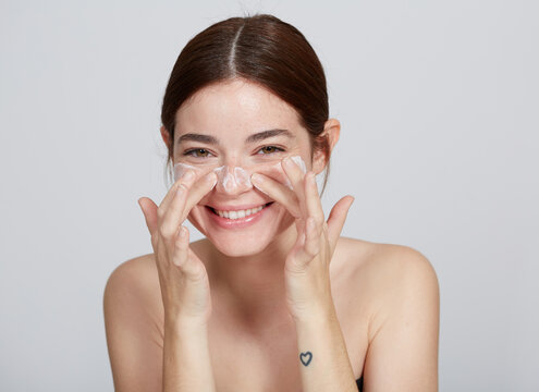 Cute Young Woman Portrait Applying Face Lotion
