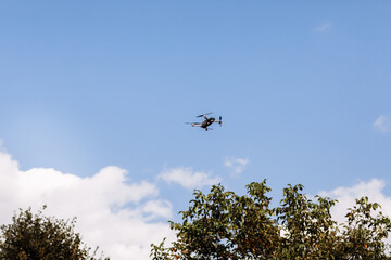 Fototapeta na wymiar Quadcopter drone in sky. Small drone flies in sky over the park taking video and photos. Remote control air delivery and spy. selective focus.