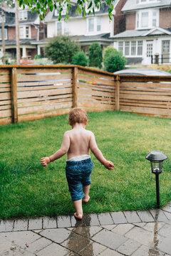Toddler walking on grass in rain