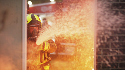 Fireman extinguish fire with the hose. Burning house fire drill. High quality photo