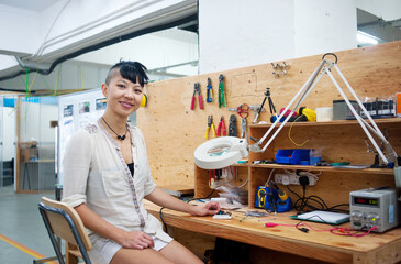 Young adult woman in workshop working on design of printed circuit board.