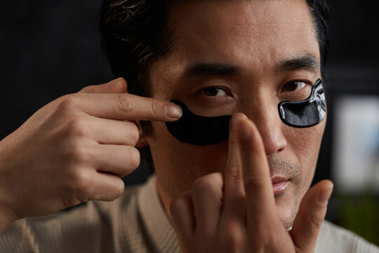 Man using under-eye collagen patch - Powered by Adobe