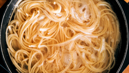 Close-up of spaghetti pasta In boiling hot water in steel pan. Preparation for making Al Dente...