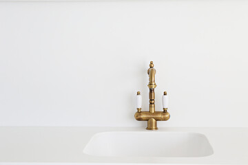 Close up shot of a vintage two handle faucet in a white minimalistic style kitchen. Copper retro styled water mixer. Copy space, background