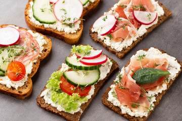 Sandwich with cereals bread and salami on dark marble background.