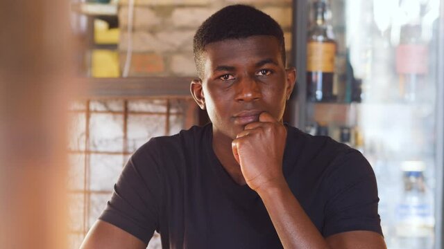 youth, confidence - black man stares at camera changes expresion and smiles