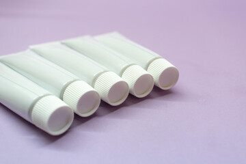 White tubes for cosmetics on a lavender background. Flatley.