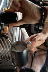 Closeup female hands are making coffee using professional metal machine in cafe.