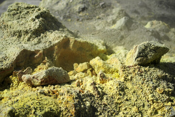 Mutnovsky volcano. Steaming fumarole close-up. Yellow crystals of sulfur on stones in the crater of the active volcano