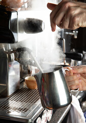 Closeup female hands are making coffee using professional metal machine in cafe.