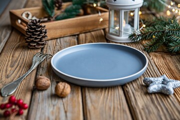 Christmas decoration. Empty plate, fork, nuts, wooden tray, lantern and green twig.