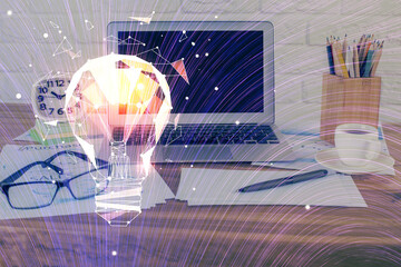 Computer on desktop in office with bulb icon hologram. Double exposure. Concept of idea.