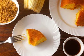 sliced corn cake on white plate on rustic wooden table for breakfast. Typical Brazilian food