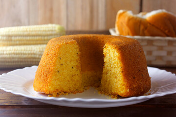 corn cake sliced on white plate on rustic wooden table. Typical Brazilian food. Front view