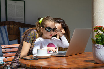 little girl surfing on laptop trackpad with woman