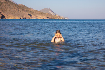 little girl with diving glasses in the water of a beach in Andalusia