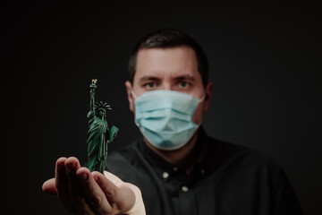 a man in a medical mask with a sculpture of the statue of liberty