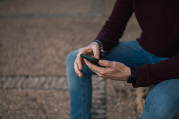 A young boy's hands using his mobile phone on the street