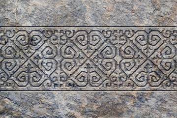 Ornamental print on the stone surface. Vintage ornament on the stone. Close-up seamless texture. Stone texture. Pattern on the stone. Embossed pattern. Wallpaper.