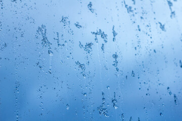 abstract background, streams of rain and snow on the glass on the background against the blue of a stormy sky
