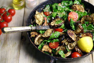 Selective focus. Macro. Warm salad with spinach and eggplant in a frying pan. Healthly food. Vegan lunch. One pan dinner