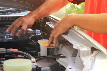 Man refills windshield wiper water on a car.