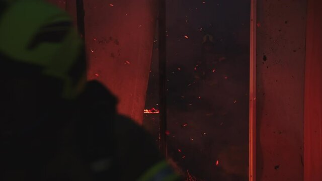 Firefighter helping to extinguish fire in burning house. High quality 4k footage
