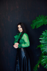 Portrait of a beautiful fashionable brunette woman in black green leaf dress