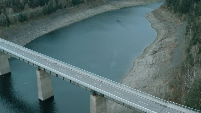 Flight over a bridge over the side basin of a dam in a German mountain range, aerial view