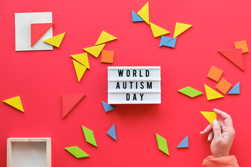 Creative design for Autism World Day on April 2, text on lightbox. Tangram elements scattered on red
