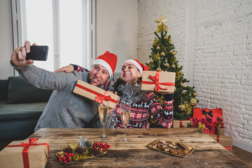 Obraz na płótnie Canvas Happy couple on mobile phone video calling friends and celebrating Virtual christmas online