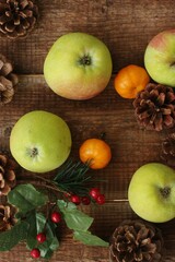 Green apples tangerines and pine cones on the table