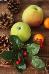 Green apples tangerines and pine cones on the table