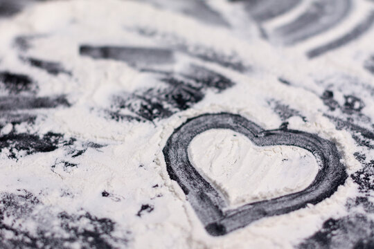 A pastry sample in the form of a heart lies on the surface with scattered flour.