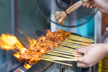Close-up series of person barbequing satay in shallow depth of field, popular food in Malaysia