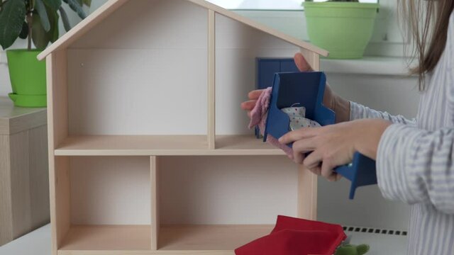 A woman housewife cleans in the room of a small daughter, a woman wipes from the dust of toys and rapes toy furniture in a dollhouse.