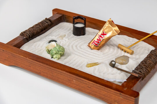 Moscow, Russia - November 19, 2020: Twix Minis candy bar lies in the middle of miniature version of Japanese rock garden (also known as dry landscape or zen garden). Illustrative editorial photography