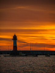 Silhouette of lighthouse at pier at sunset
