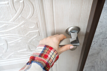 Female hand holds a front door handle close-up