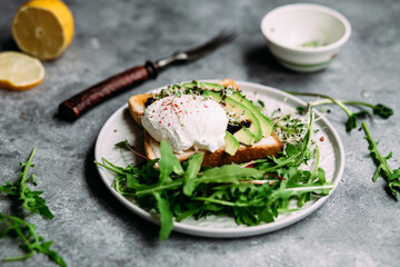 Poached egg with avocado salad, microgreen and arugula