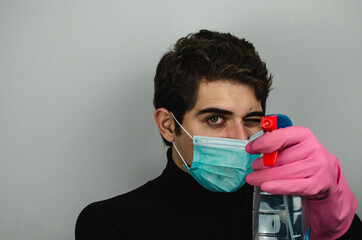 hombre joven con mascarilla guantes y desinfectante limpiando